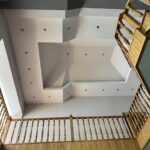 Interior view of a staircase with wooden railings and a modern ceiling design